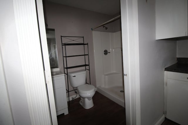 bathroom featuring hardwood / wood-style floors, walk in shower, toilet, and vanity