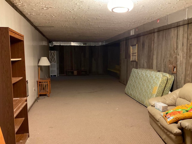 basement featuring wooden walls, light colored carpet, and a textured ceiling