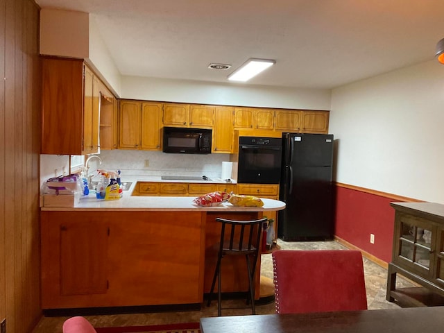 kitchen featuring kitchen peninsula, light tile floors, black appliances, and sink