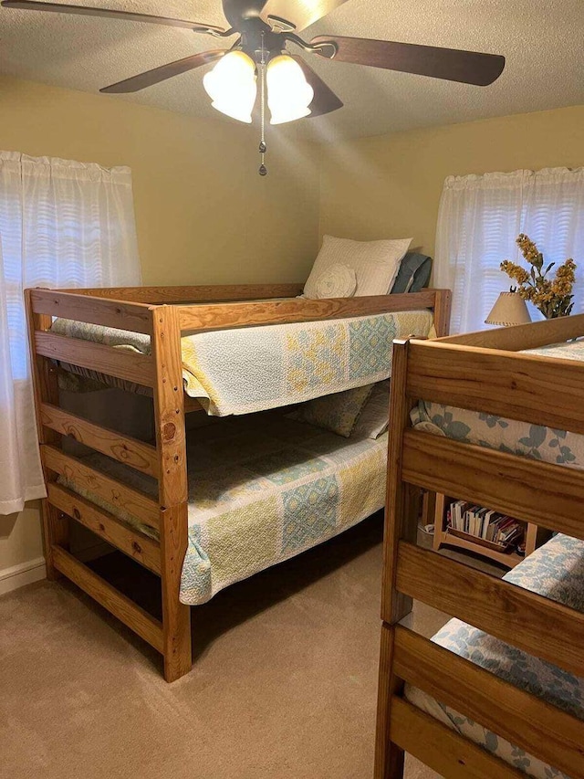 bedroom featuring ceiling fan, light colored carpet, and a textured ceiling