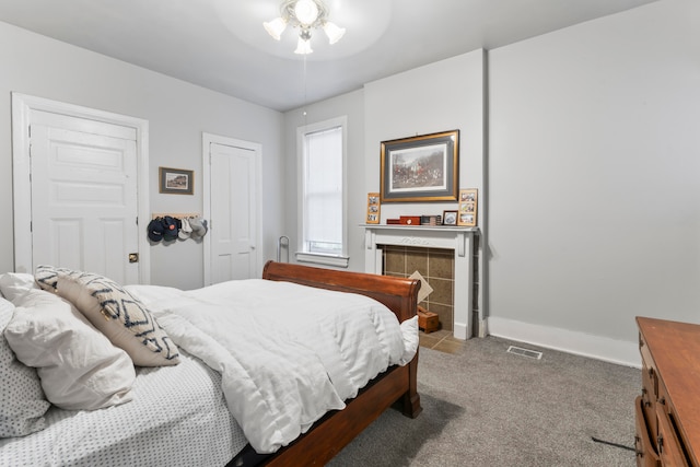 carpeted bedroom with ceiling fan and a tile fireplace