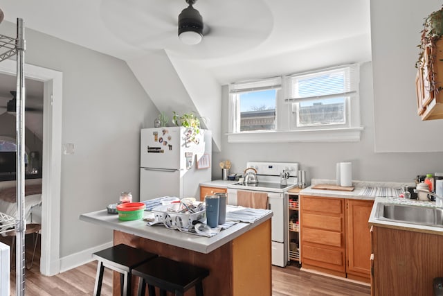 kitchen with vaulted ceiling, light hardwood / wood-style flooring, ceiling fan, sink, and white appliances