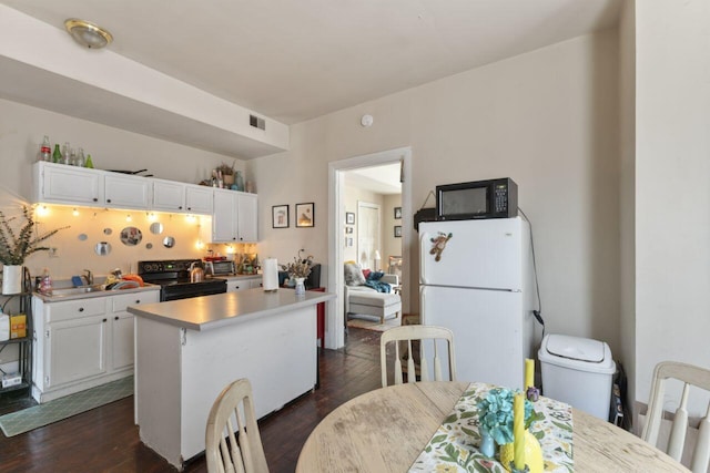 kitchen featuring white fridge, dark hardwood / wood-style flooring, range, a center island, and white cabinetry