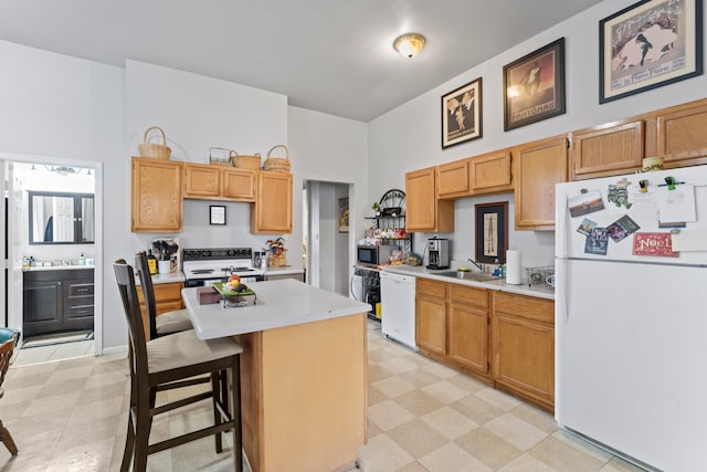 kitchen with sink, a breakfast bar, white appliances, and light tile floors