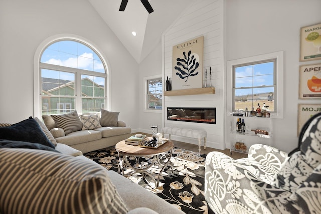 living room with ceiling fan, hardwood / wood-style floors, and high vaulted ceiling