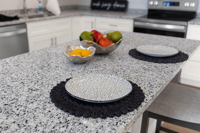 room details with light stone countertops, white cabinetry, appliances with stainless steel finishes, and sink