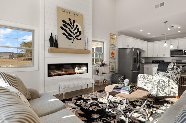 living room featuring a towering ceiling, dark hardwood / wood-style floors, and a large fireplace