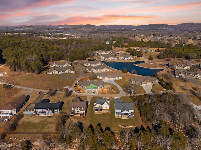 aerial view at dusk featuring a water view