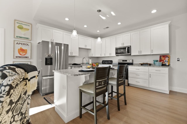 kitchen with white cabinetry, light stone counters, and stainless steel appliances