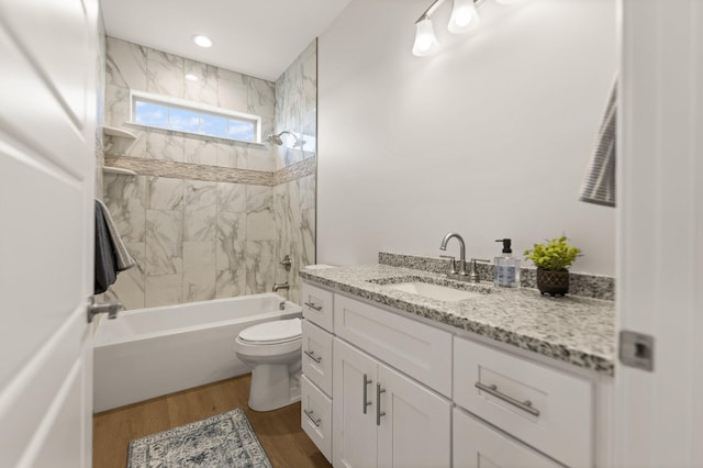 full bathroom with vanity, tiled shower / bath combo, wood-type flooring, and toilet