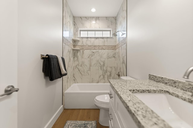 full bathroom with hardwood / wood-style flooring, vanity, tiled shower / bath, and toilet