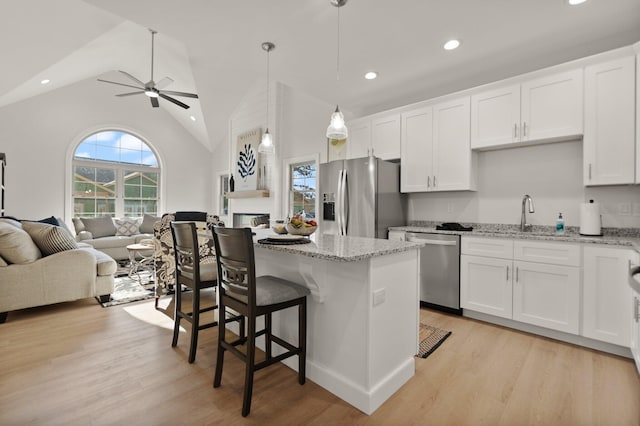 kitchen featuring appliances with stainless steel finishes, white cabinetry, sink, hanging light fixtures, and light stone countertops