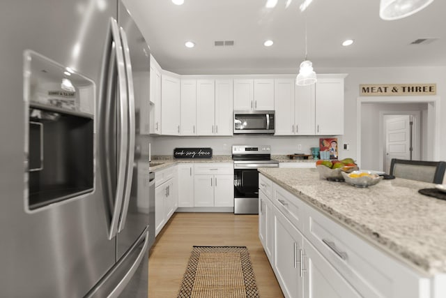 kitchen with white cabinetry, decorative light fixtures, light stone countertops, and appliances with stainless steel finishes