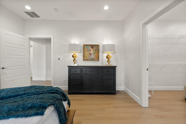 bedroom with a spacious closet and light hardwood / wood-style floors