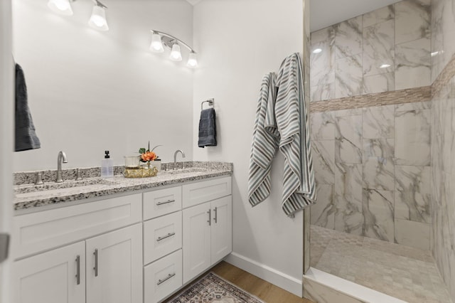 bathroom featuring vanity, wood-type flooring, and a tile shower