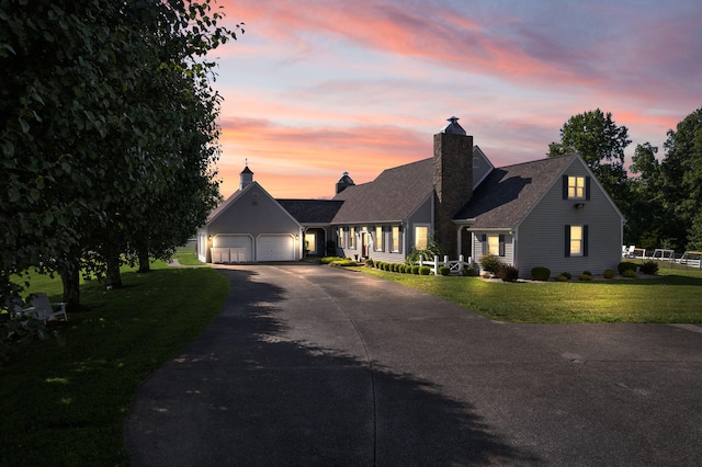 new england style home featuring a yard and a garage