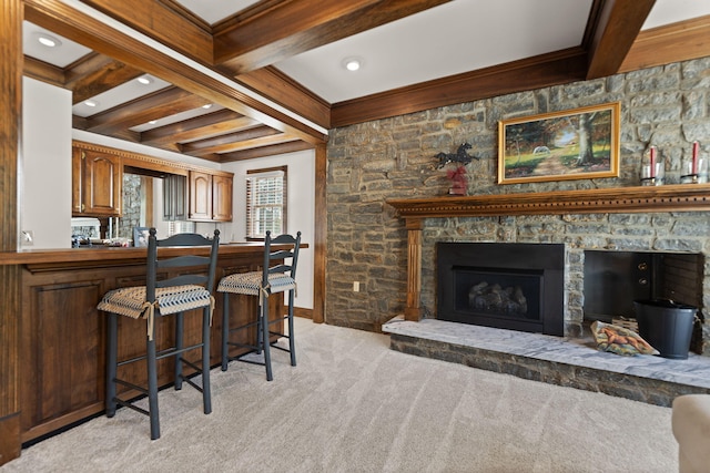 interior space with a stone fireplace, beamed ceiling, and light carpet