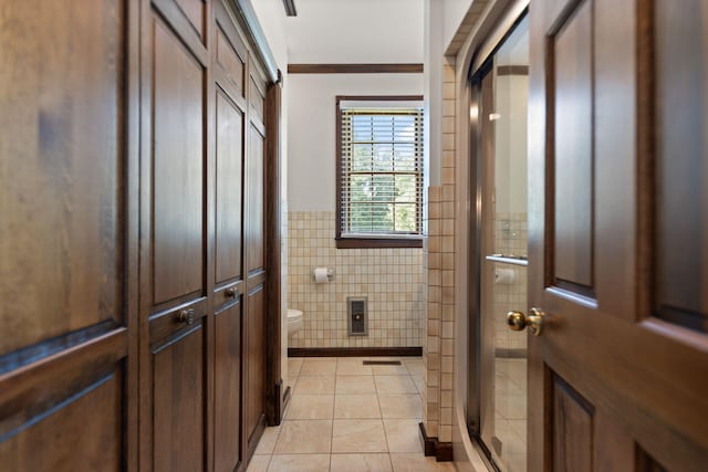 bathroom with toilet, walk in shower, tile walls, crown molding, and tile patterned flooring