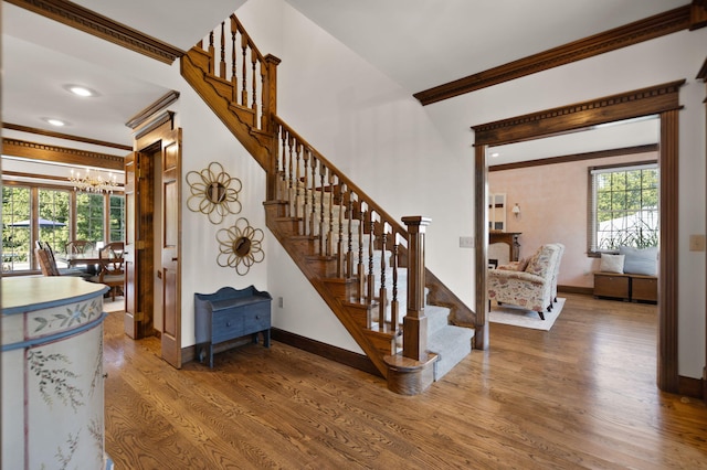 stairway with hardwood / wood-style flooring, crown molding, and a notable chandelier