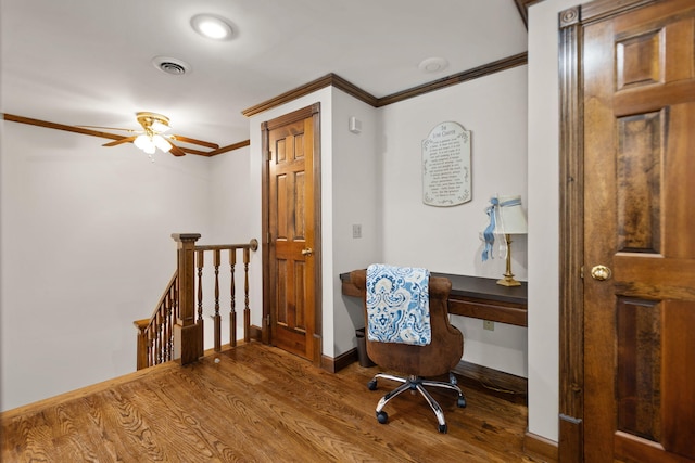 office with wood-type flooring, built in desk, crown molding, and ceiling fan