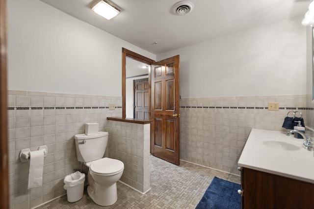 bathroom featuring tile patterned flooring, vanity, tile walls, and toilet