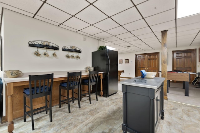 kitchen with a drop ceiling, black fridge, a kitchen bar, and billiards