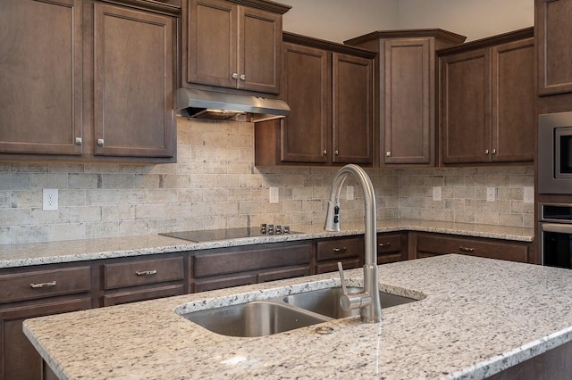 kitchen featuring appliances with stainless steel finishes, dark brown cabinets, backsplash, and light stone counters