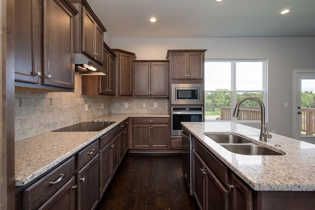 kitchen featuring dark hardwood / wood-style flooring, appliances with stainless steel finishes, light stone countertops, and sink