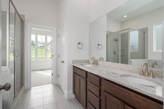 bathroom featuring a shower with shower door, oversized vanity, double sink, and tile flooring