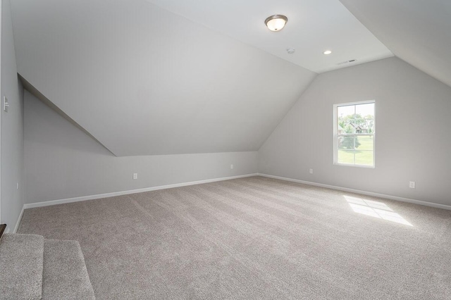 bonus room with lofted ceiling and light carpet