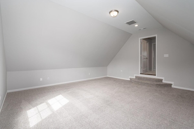 bonus room with light carpet and vaulted ceiling