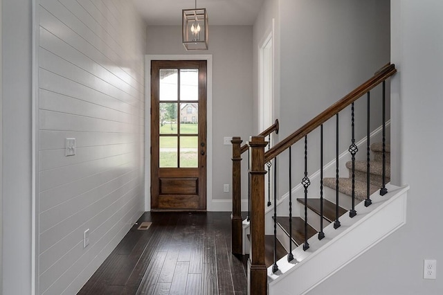 entryway with wooden walls and dark wood-type flooring