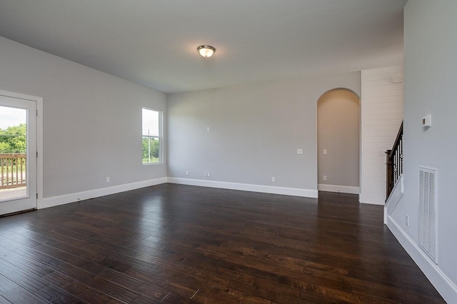 empty room featuring dark wood-type flooring and a wealth of natural light