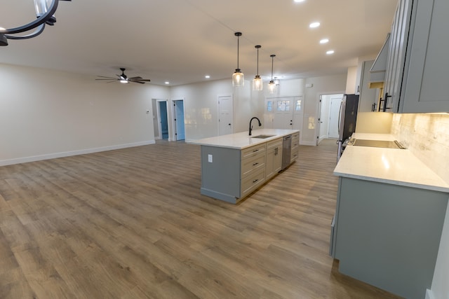 kitchen featuring hardwood / wood-style floors, sink, a kitchen island with sink, gray cabinets, and pendant lighting