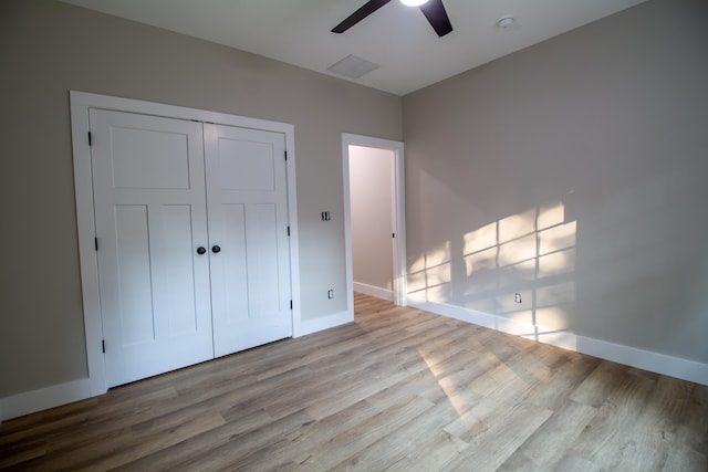 unfurnished bedroom with ceiling fan, a closet, and light wood-type flooring