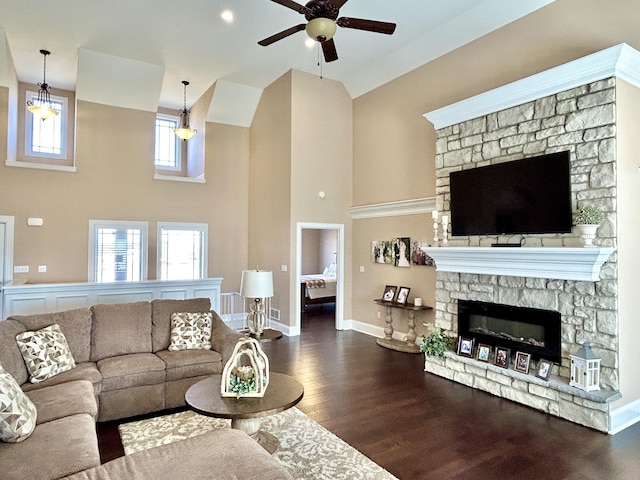 living room featuring a stone fireplace, high vaulted ceiling, dark hardwood / wood-style floors, and ceiling fan