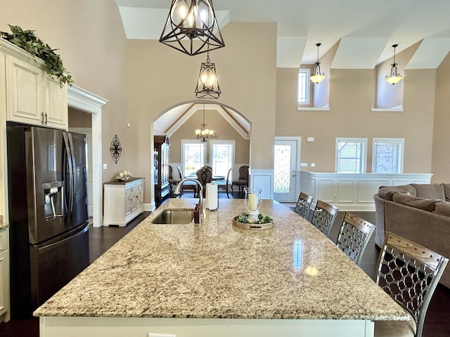 kitchen featuring sink, a chandelier, hanging light fixtures, stainless steel fridge, and a kitchen breakfast bar