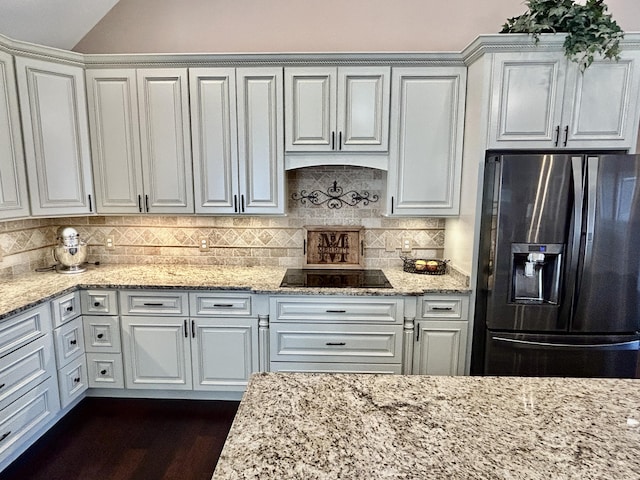 kitchen with white cabinetry, stainless steel fridge, light stone countertops, and decorative backsplash