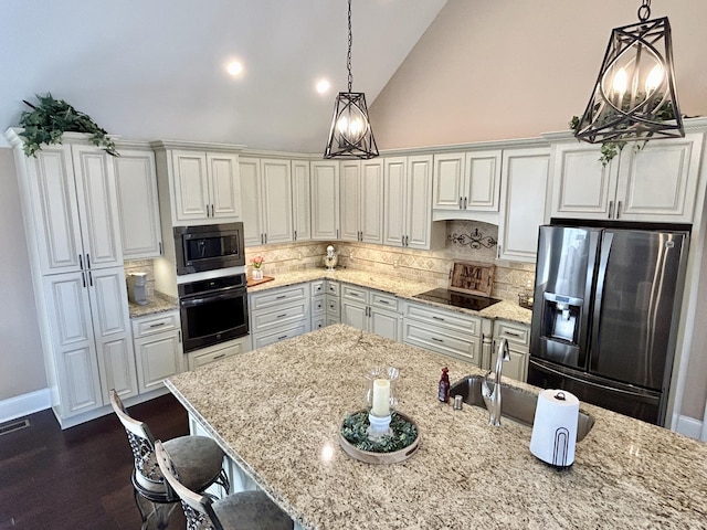 kitchen with white cabinetry, light stone counters, hanging light fixtures, and black appliances