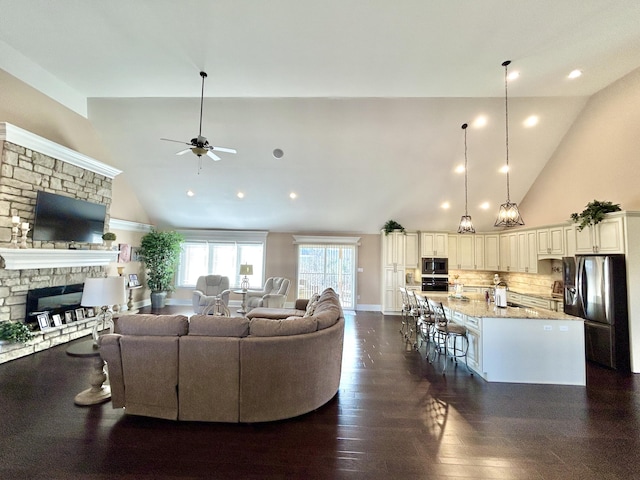 living room featuring dark hardwood / wood-style floors, ceiling fan, a fireplace, and high vaulted ceiling