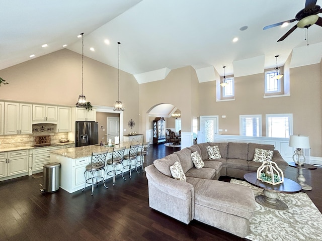 living room with ceiling fan, dark hardwood / wood-style floors, sink, and high vaulted ceiling