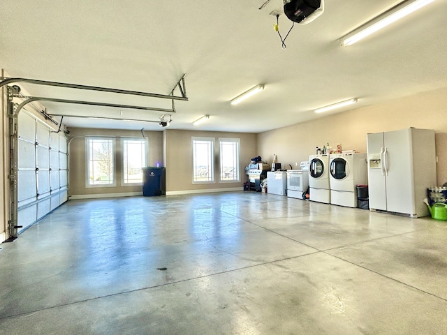 garage featuring a garage door opener, washing machine and dryer, and white refrigerator with ice dispenser