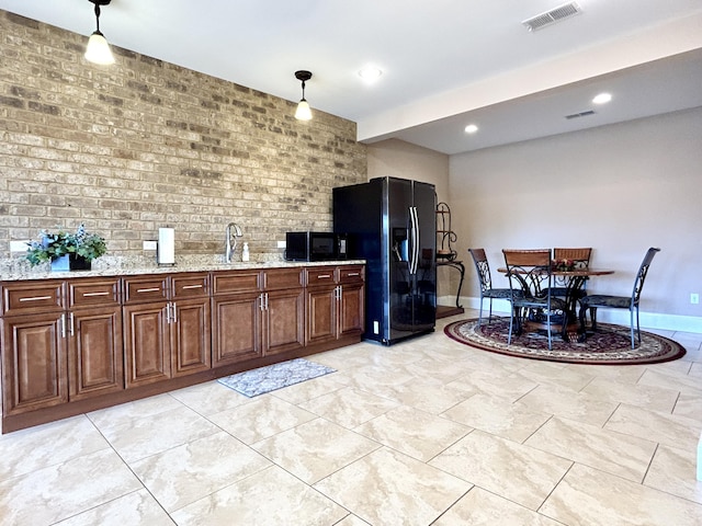 kitchen with sink, brick wall, decorative light fixtures, and black refrigerator with ice dispenser