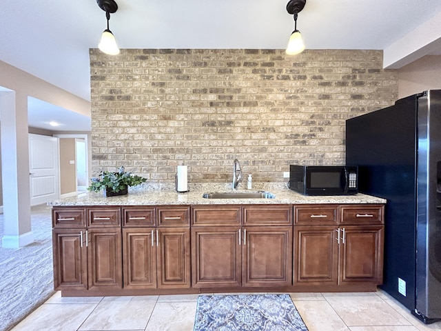 kitchen featuring stainless steel fridge, decorative light fixtures, light stone countertops, and sink