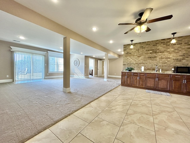 interior space featuring brick wall, light carpet, ceiling fan, and wet bar