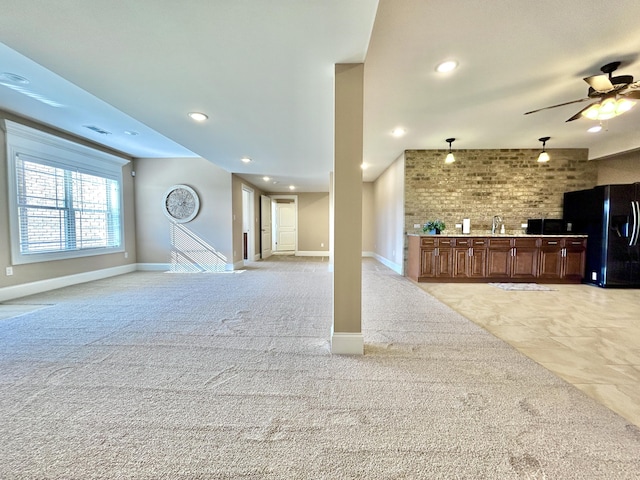 unfurnished living room with light carpet, sink, and ceiling fan