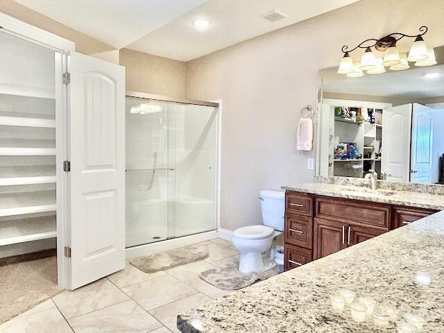 bathroom with vanity, toilet, and a shower with door