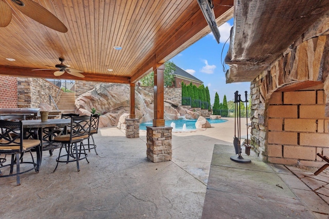 kitchen featuring a kitchen island, pendant lighting, stainless steel appliances, ceiling fan, and light stone counters