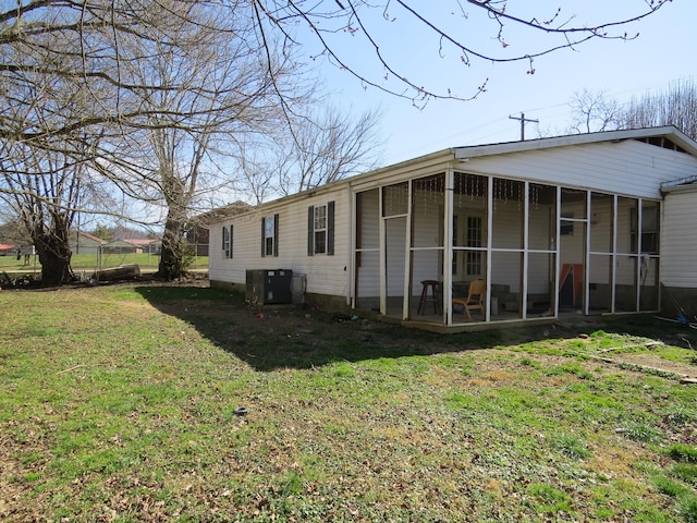 rear view of property featuring a yard, central air condition unit, and a sunroom