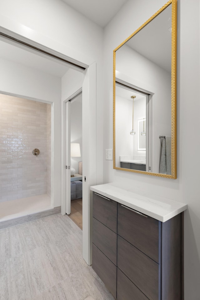 bathroom featuring vanity, hardwood / wood-style flooring, and a tile shower